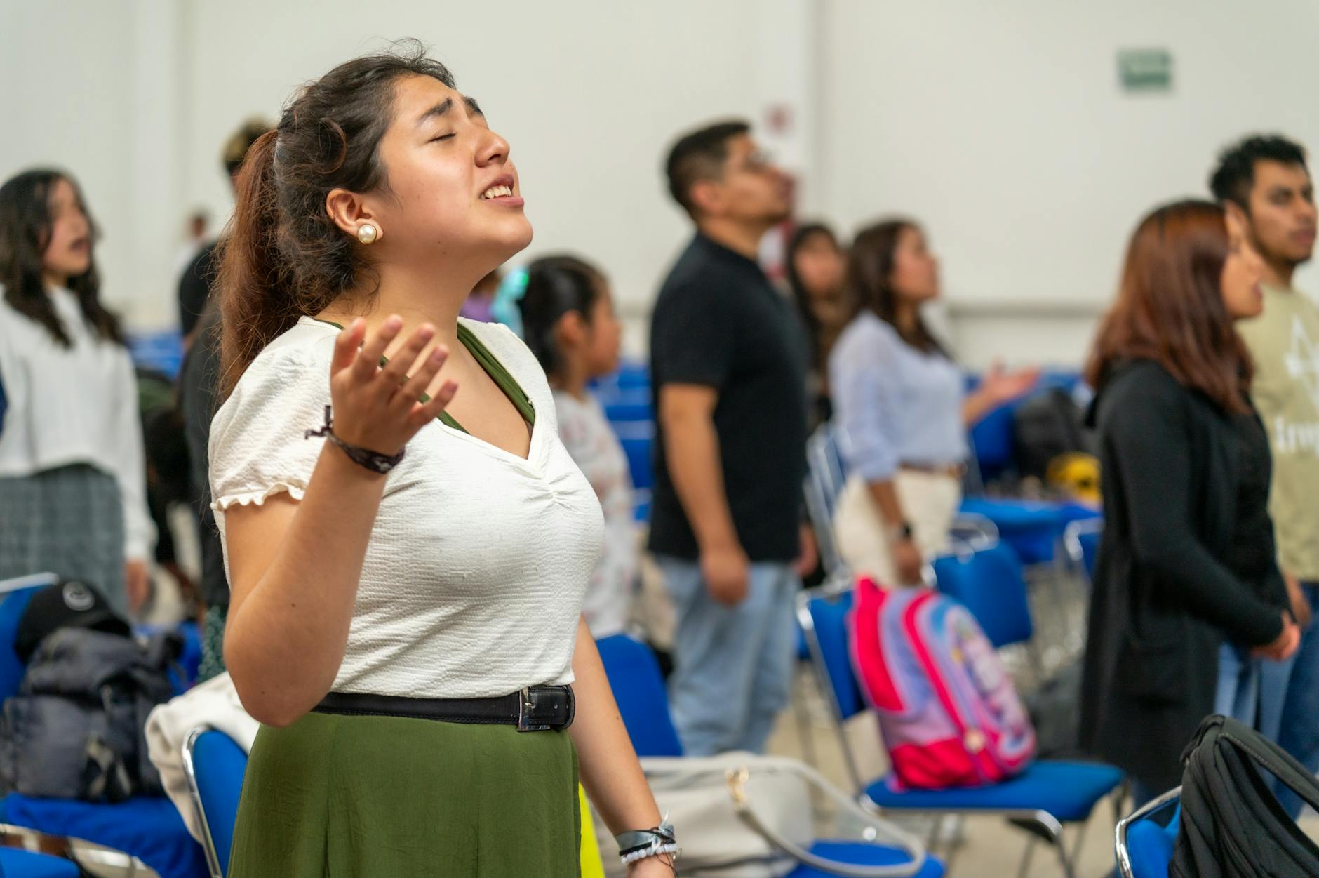 Młodzi dorośli z uniesionymi rękami podczas modlitwy wewnątrz kościoła