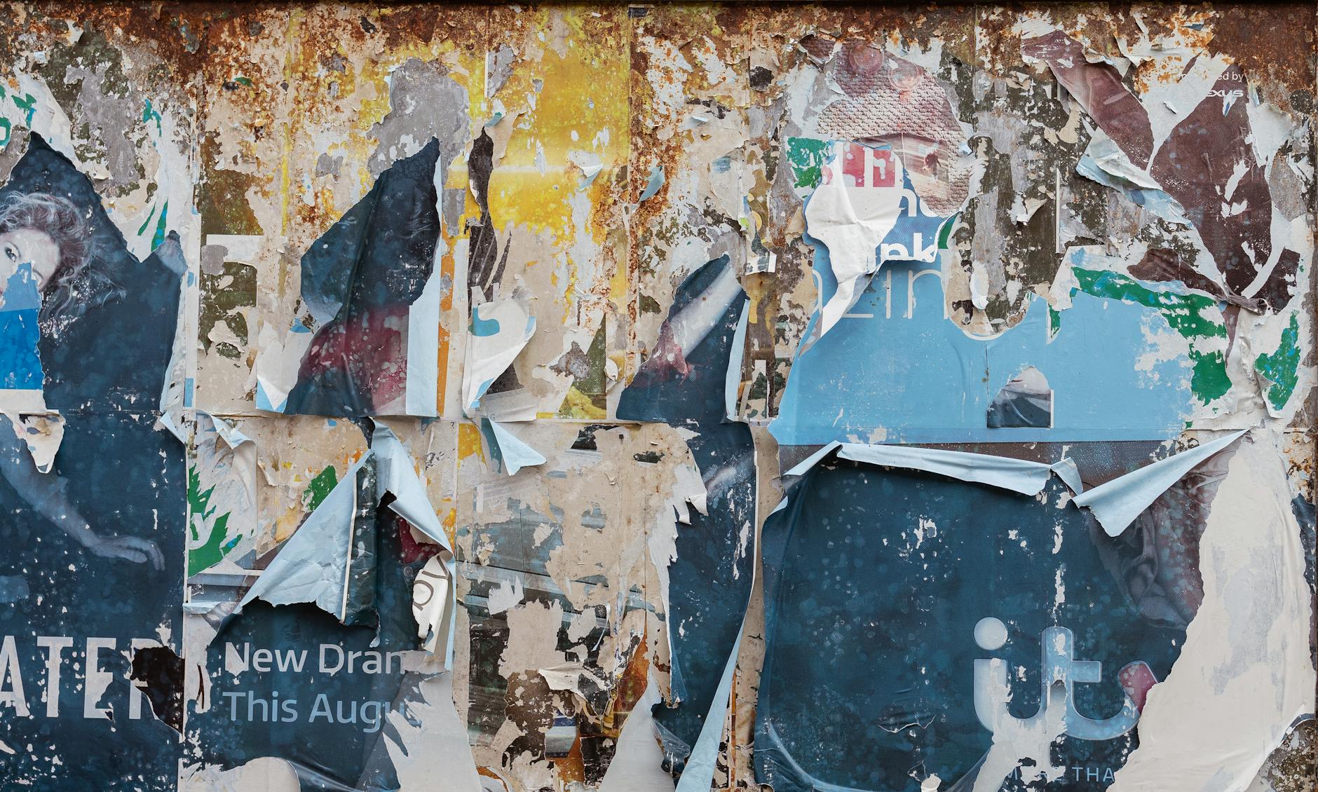 Poszarpane warstwowe plakaty na zardzewiałej tablicy ogłoszeń