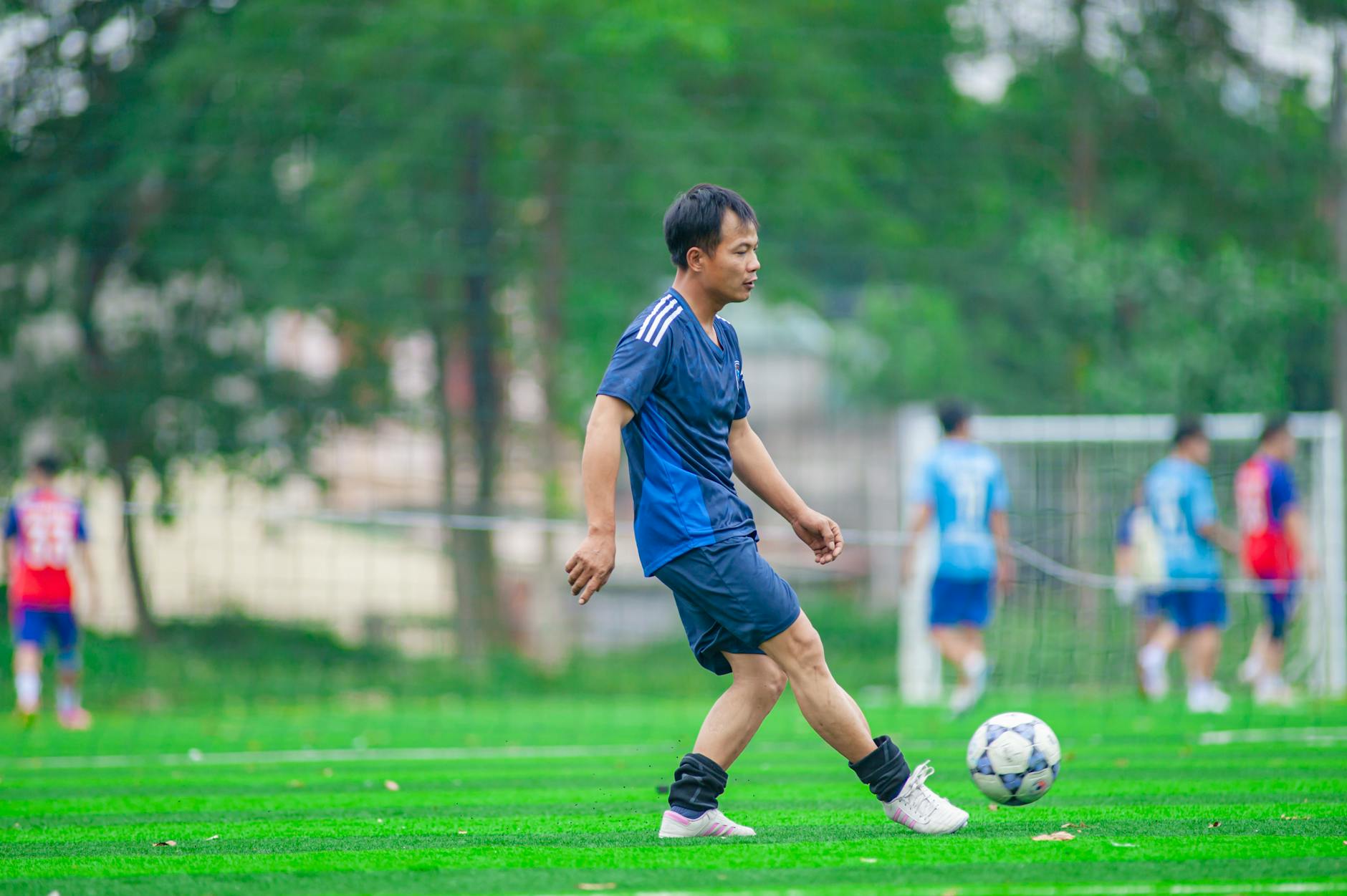 Amatorski zawodnik futsalu ćwiczy na boisku z kolegami w tle
