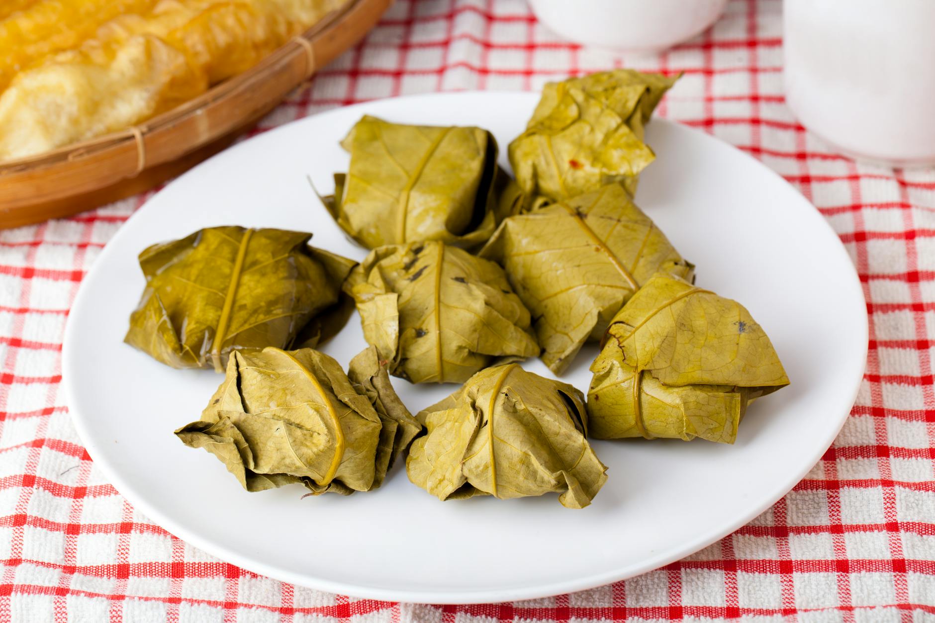 Indonezyjski deser tape ketan w liściach bananowca na białym talerzu