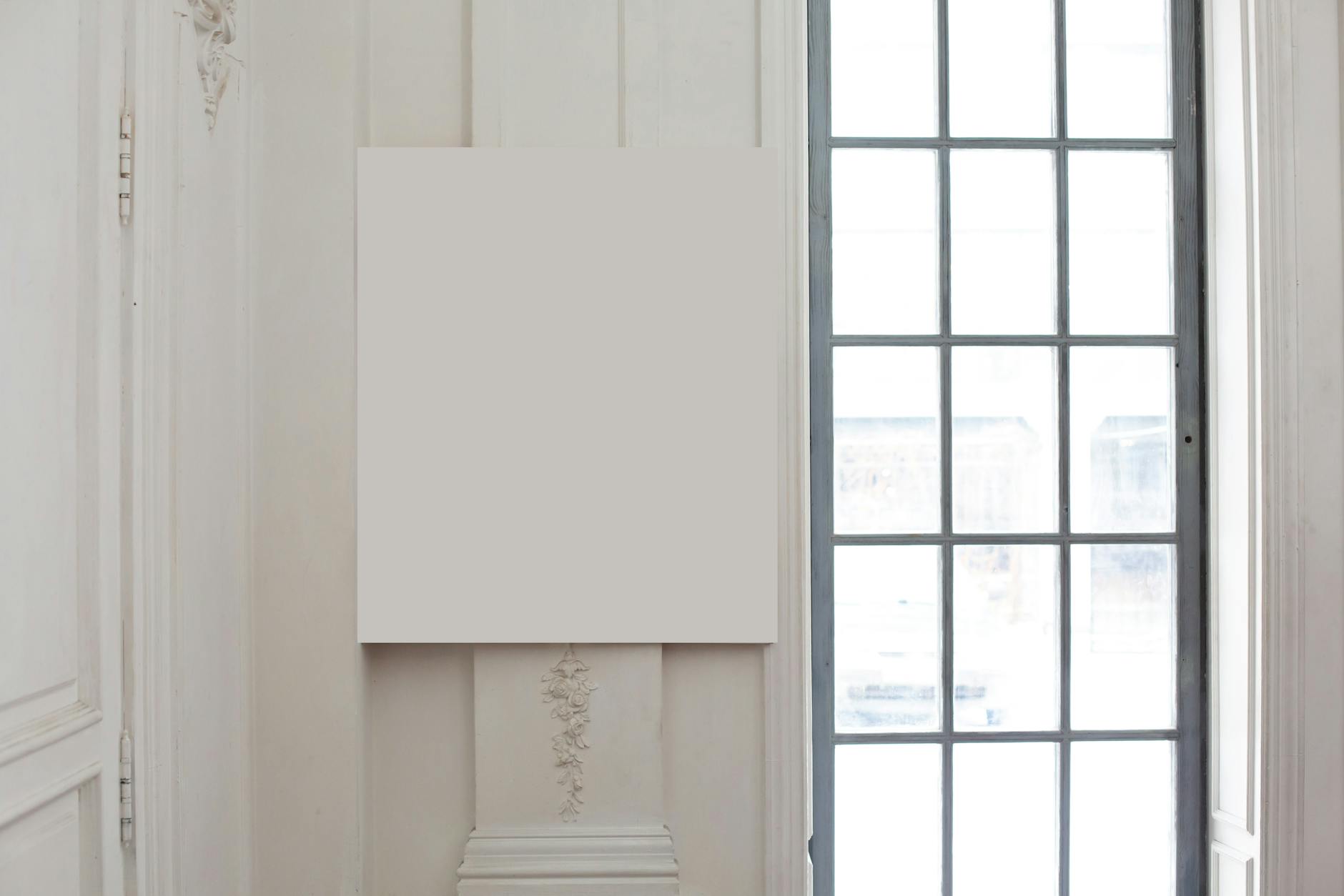 Puste białe płótno na ozdobnej ścianie w jasnym, klasycznym wnętrzu