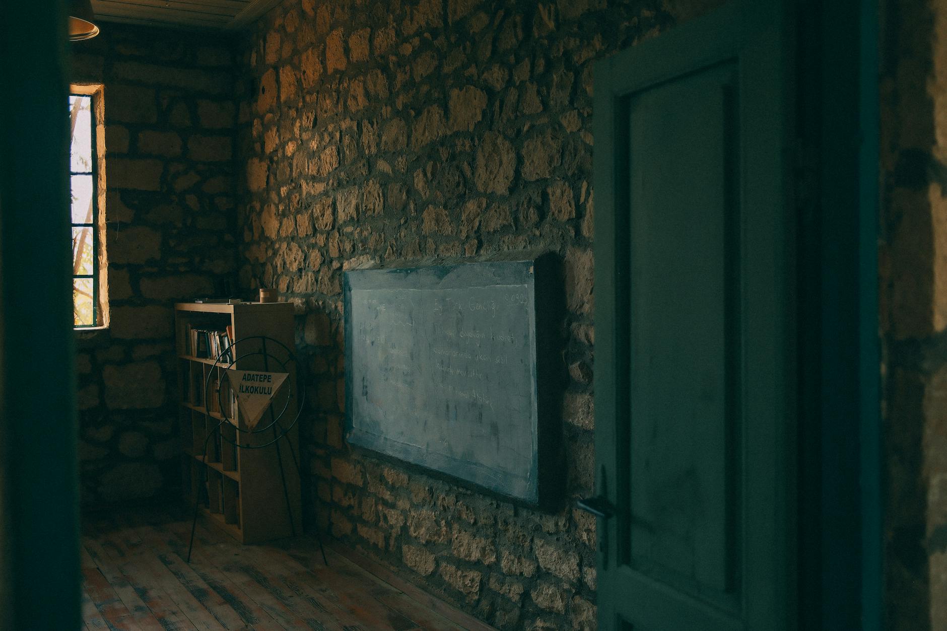 Stara klasa z kamiennymi ścianami, drewnianą półką i szkolną tablicą